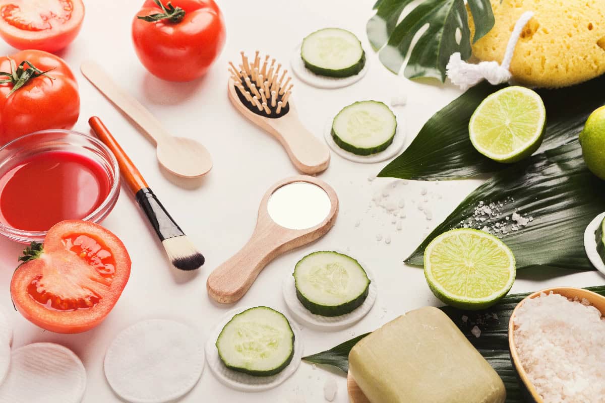 DIY vegan skincare ingredients like cucumber, tomato, lime, and natural tools arranged on a white background.