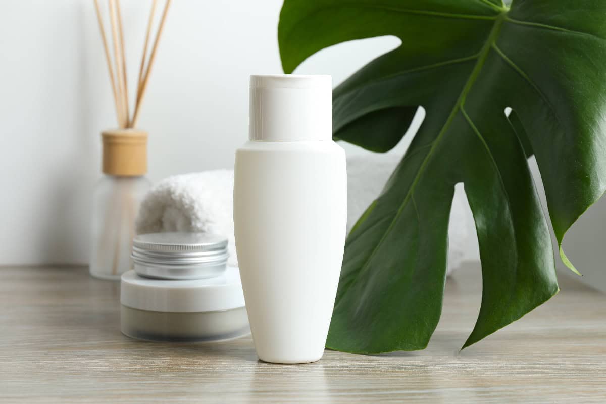 Simple vegan skincare products with a clean bottle and green leaf, symbolizing natural beauty and plant-based care.