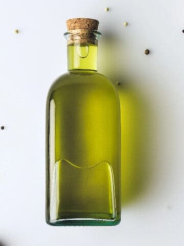 Extra virgin olive oil in a glass bottle with olives, a heart-healthy vegan fat source.