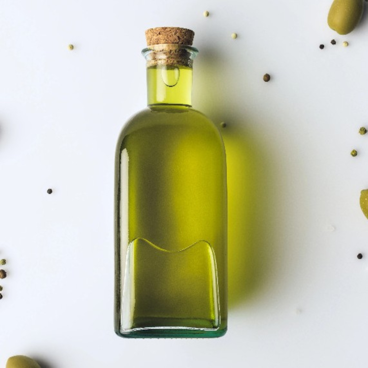 Extra virgin olive oil in a glass bottle with olives, a heart-healthy vegan fat source.