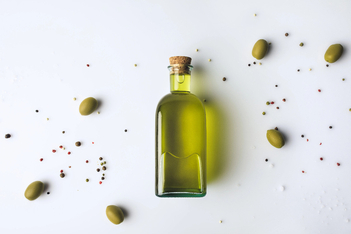 Extra virgin olive oil in a glass bottle with olives, a healthy vegan fat source.
