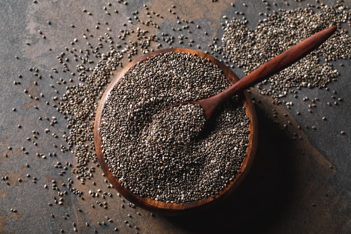 Chia seeds in a wooden bowl with a spoon, a popular vegan source of fiber and healthy fats.