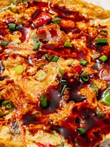 Vegetable egg foo young topped with savory brown sauce and green onions over steamed rice.