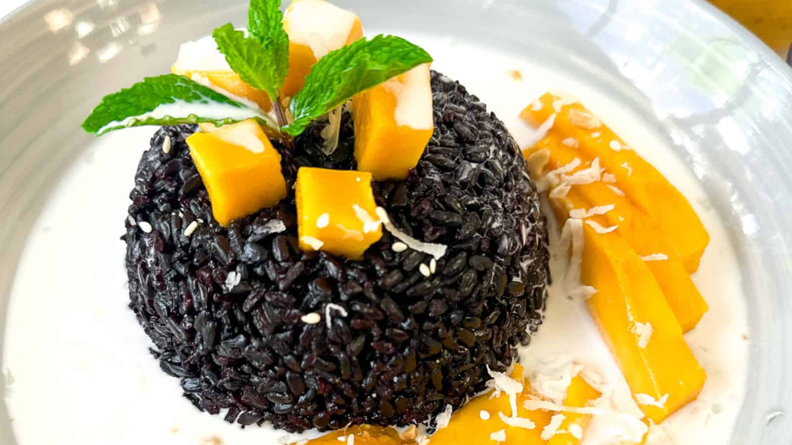 Black rice pudding in a creamy coconut bath with mango,coconut flakes and mint.