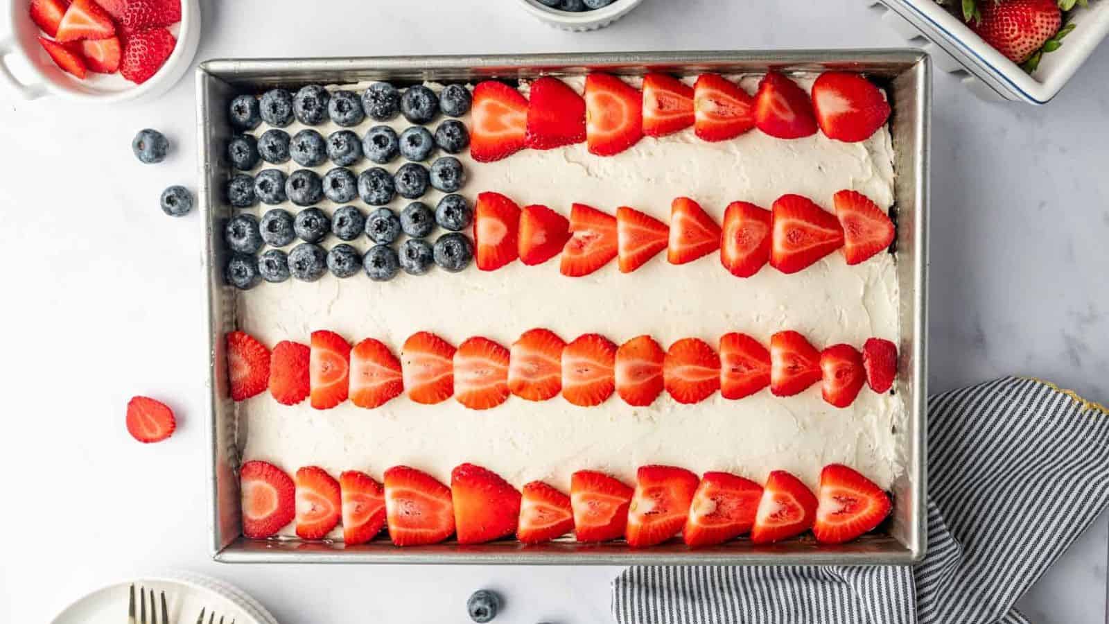 Sheet cake decorated like an American flag with berries and frosting.