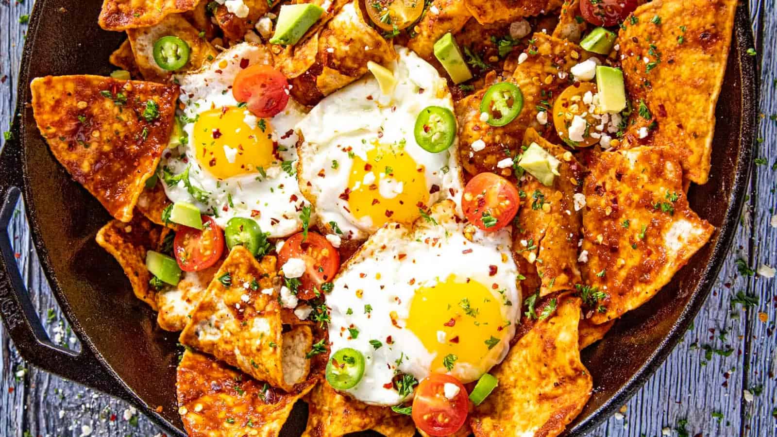 Chilaquiles topped with red sauce, crispy tortillas, and garnishes.