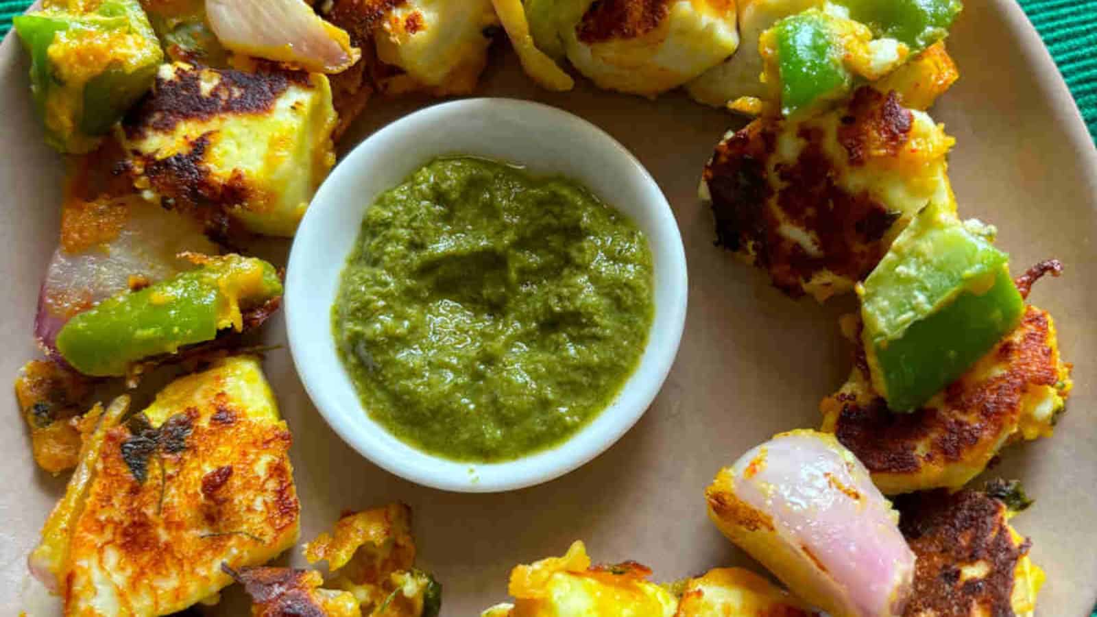 Paneer tikka cooked with spices and vegetables until lightly charred.