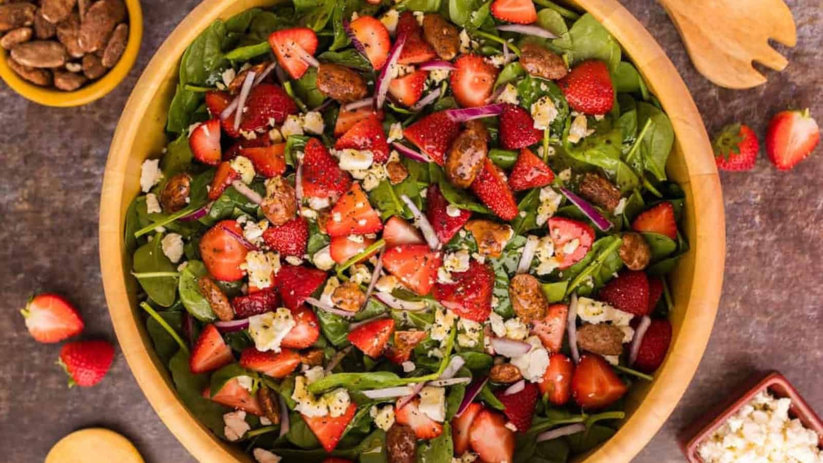 Spinach salad topped with strawberries, artichokes, and dressing.