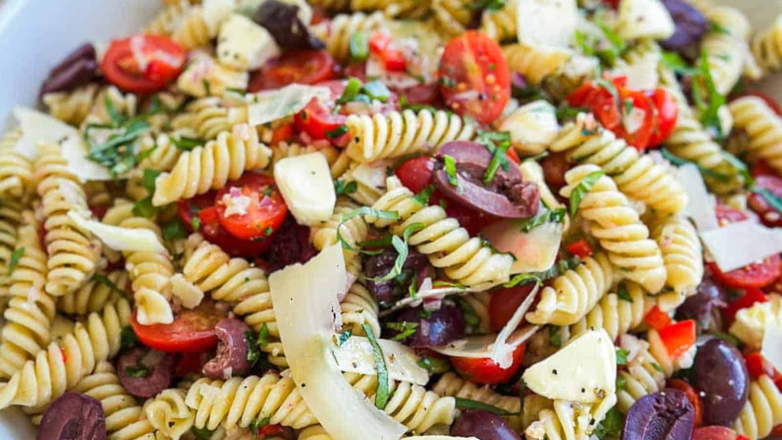 Italian pasta salad mixed with vegetables and herbs in dressing.