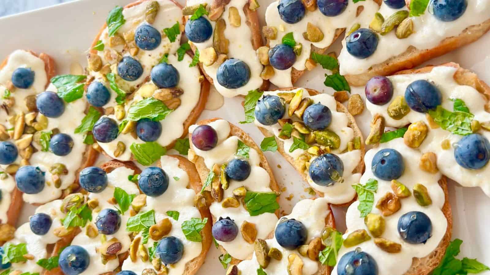 Crostini topped with watermelon, feta, and blueberries on toasted bread slices.