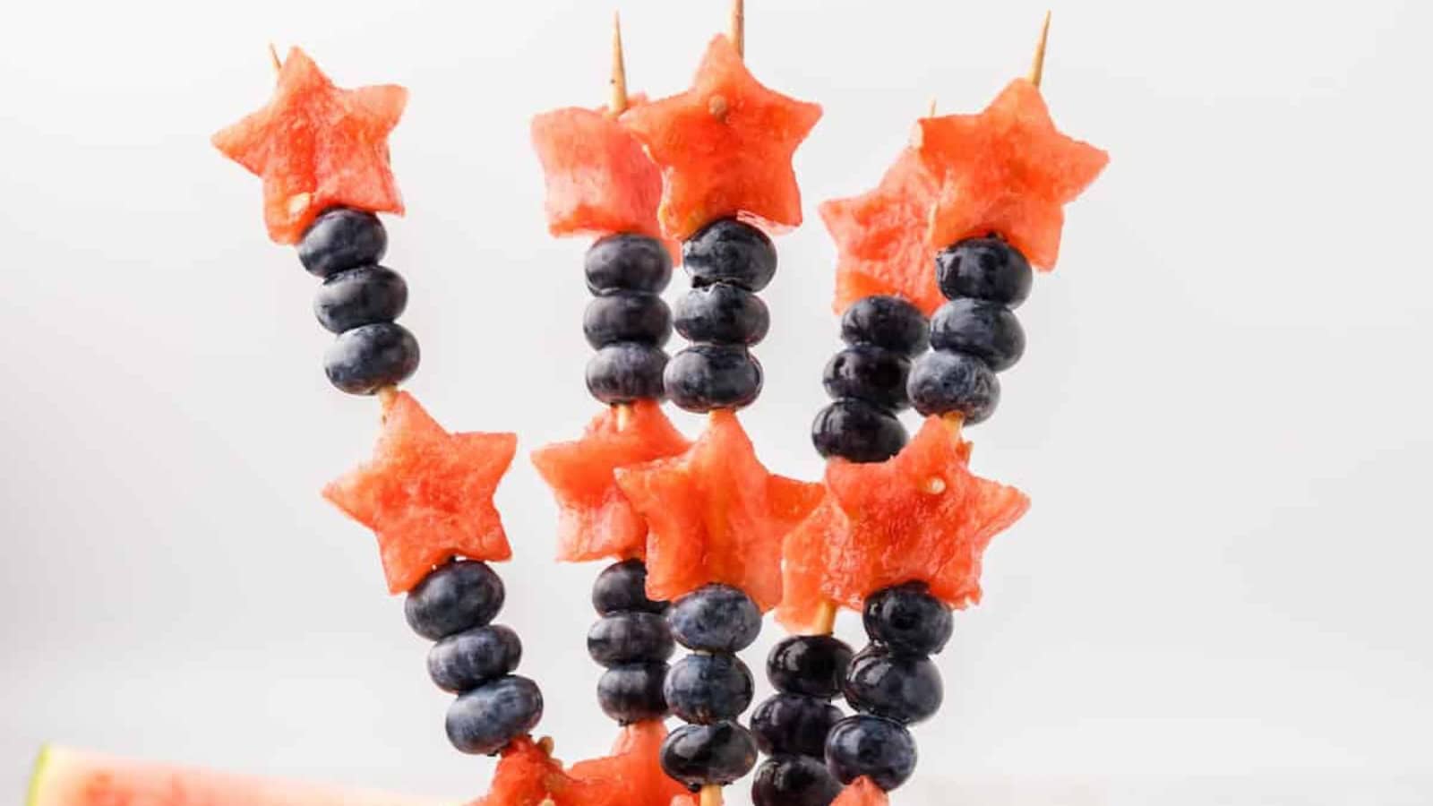 Watermelon slices cut into star shapes on skewers for a festive treat.