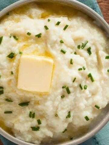 Mashed cauliflower potatoes with butter on top in a bowl.