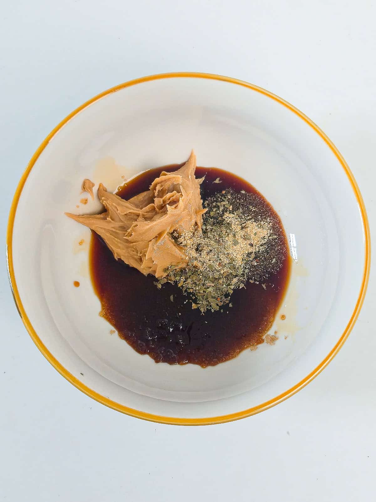 Peanut butter, soy sauce, and seasonings in a bowl for peanut satay tofu marinade.