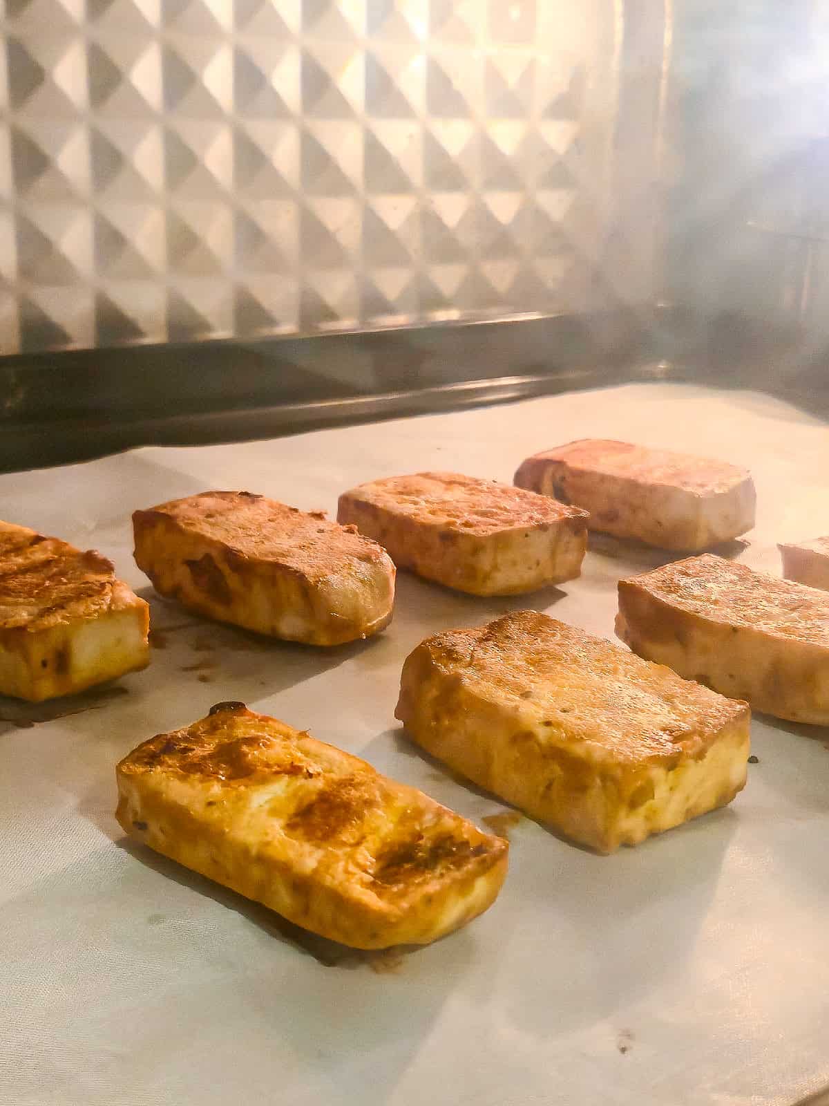 Marinated tofu baking in the oven until golden brown and lightly crispy on the edges.