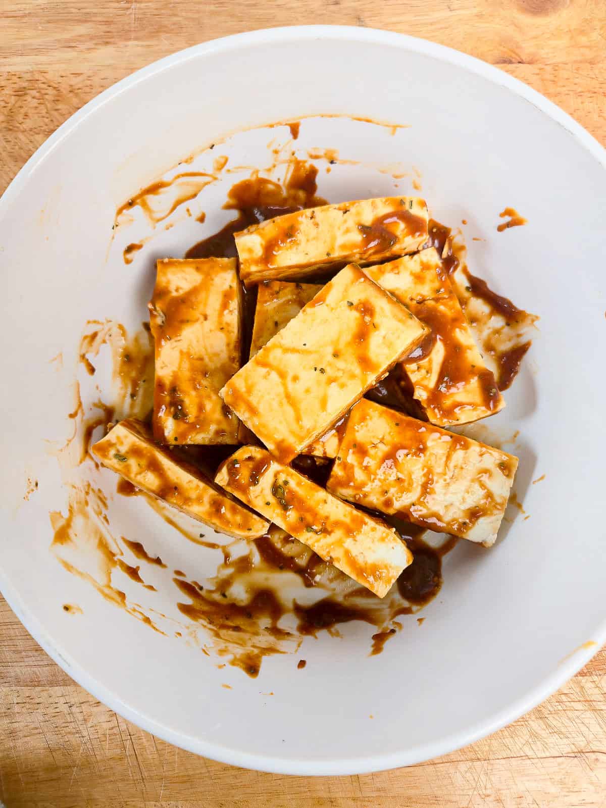 Tofu pieces coated evenly with peanut satay marinade before baking.