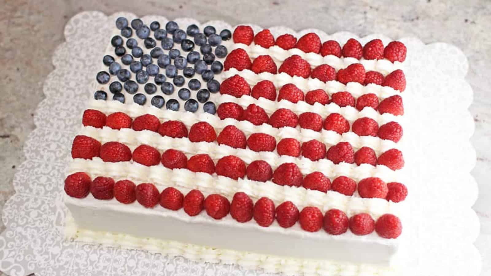American flag cake decorated with blueberries, raspberries, and frosting.