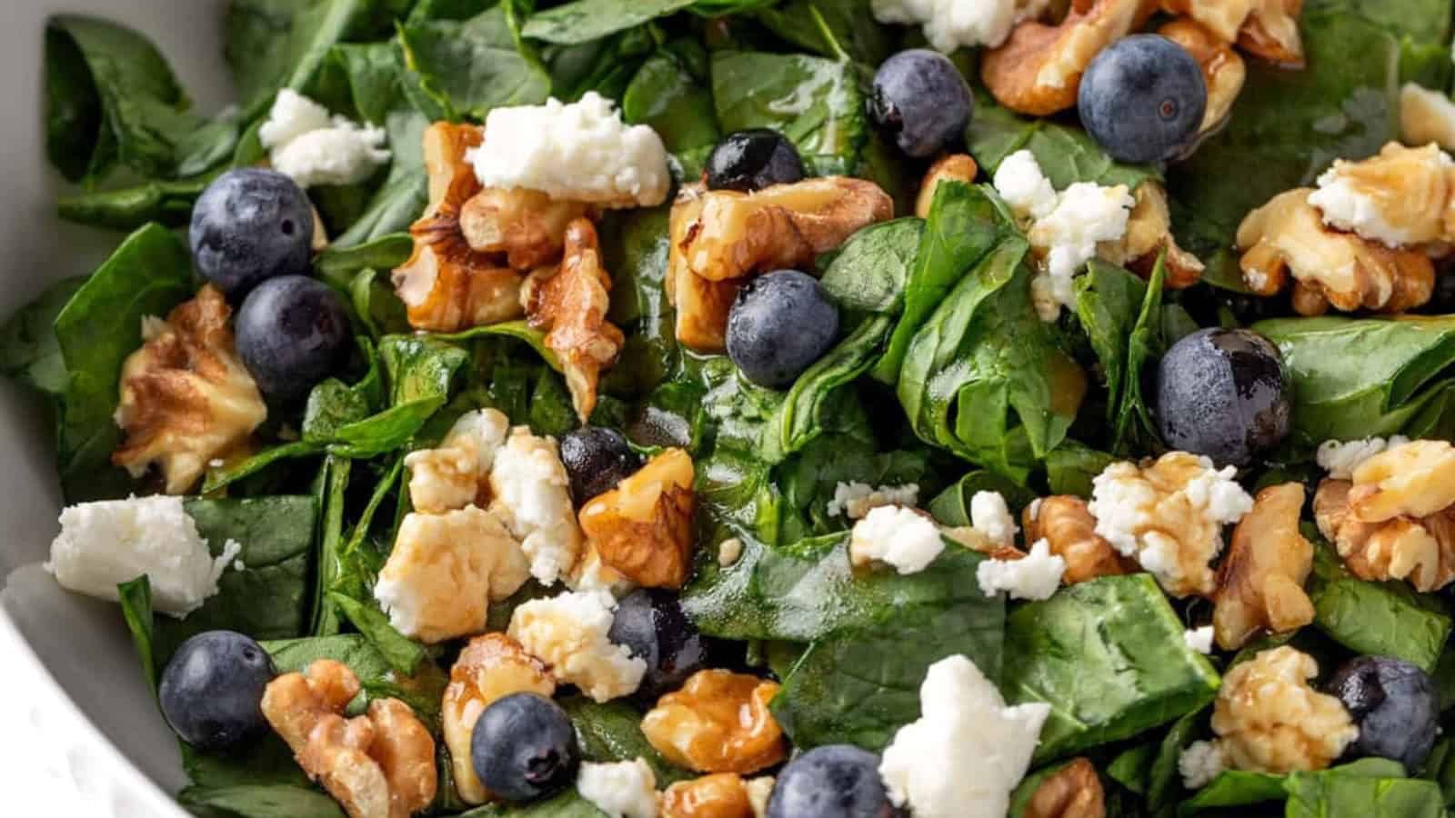 Blueberry goat cheese salad with leafy greens and a sprinkle of crunchy toppings.