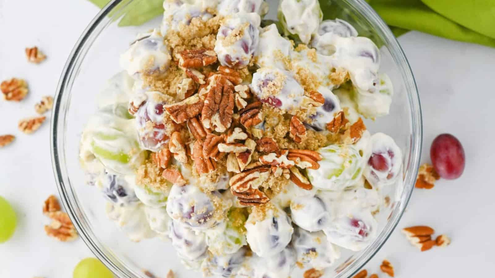 Creamy grape salad topped with brown sugar and crunchy pecans in a serving bowl.