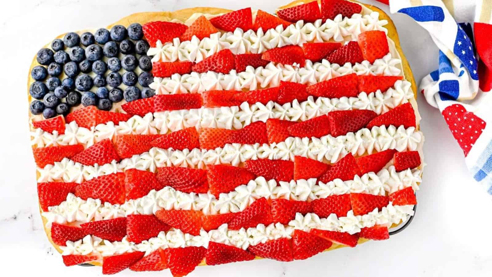 Cookie cake decorated with frosting and berries in an American flag design.