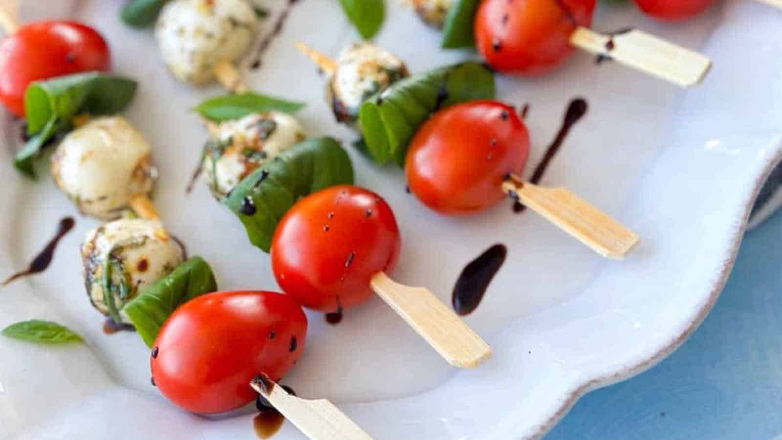 Caprese skewers layered with tomatoes, mozzarella, and basil leaves.