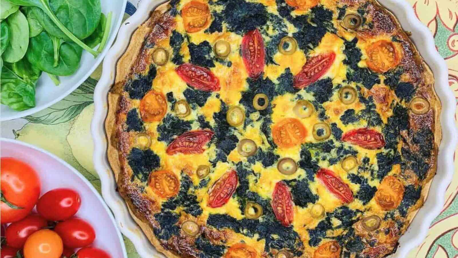 Quiche filled with spinach, cherry tomatoes, and a golden crust.