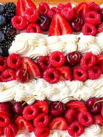 Patriotic flag cake decorated with fresh berries and white frosting.