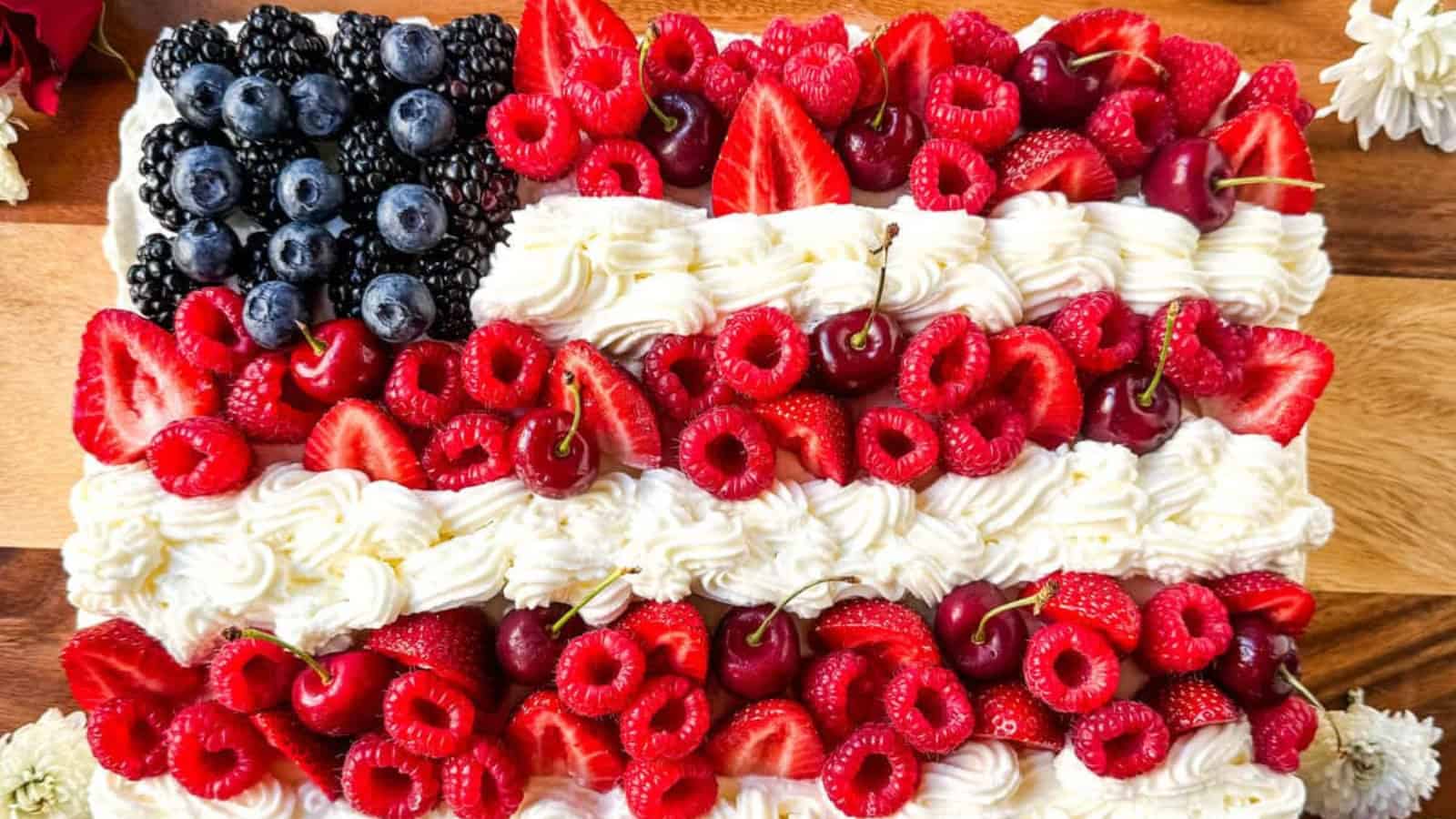 Patriotic flag cake decorated with fresh berries and white frosting.