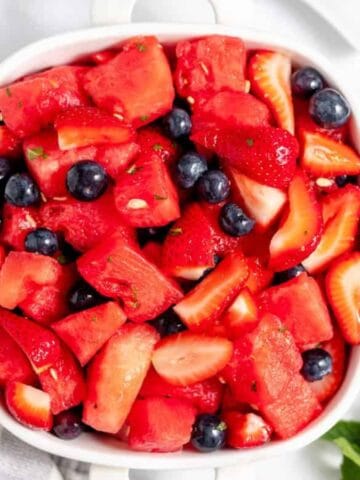 Festive fruit salad made with strawberries, blueberries, and mini marshmallows.