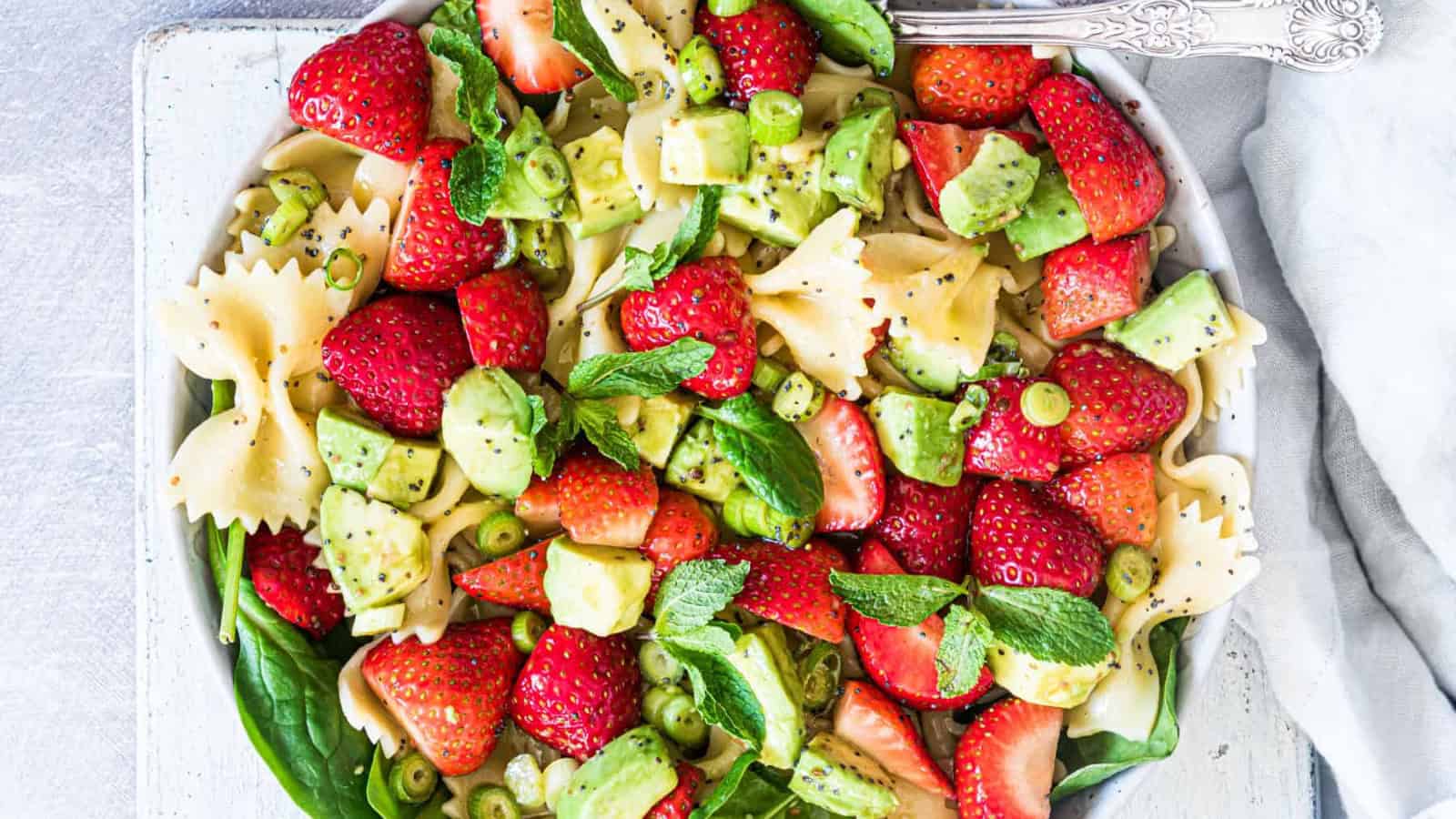 Pasta salad with strawberries, avocado, and a light dressing.