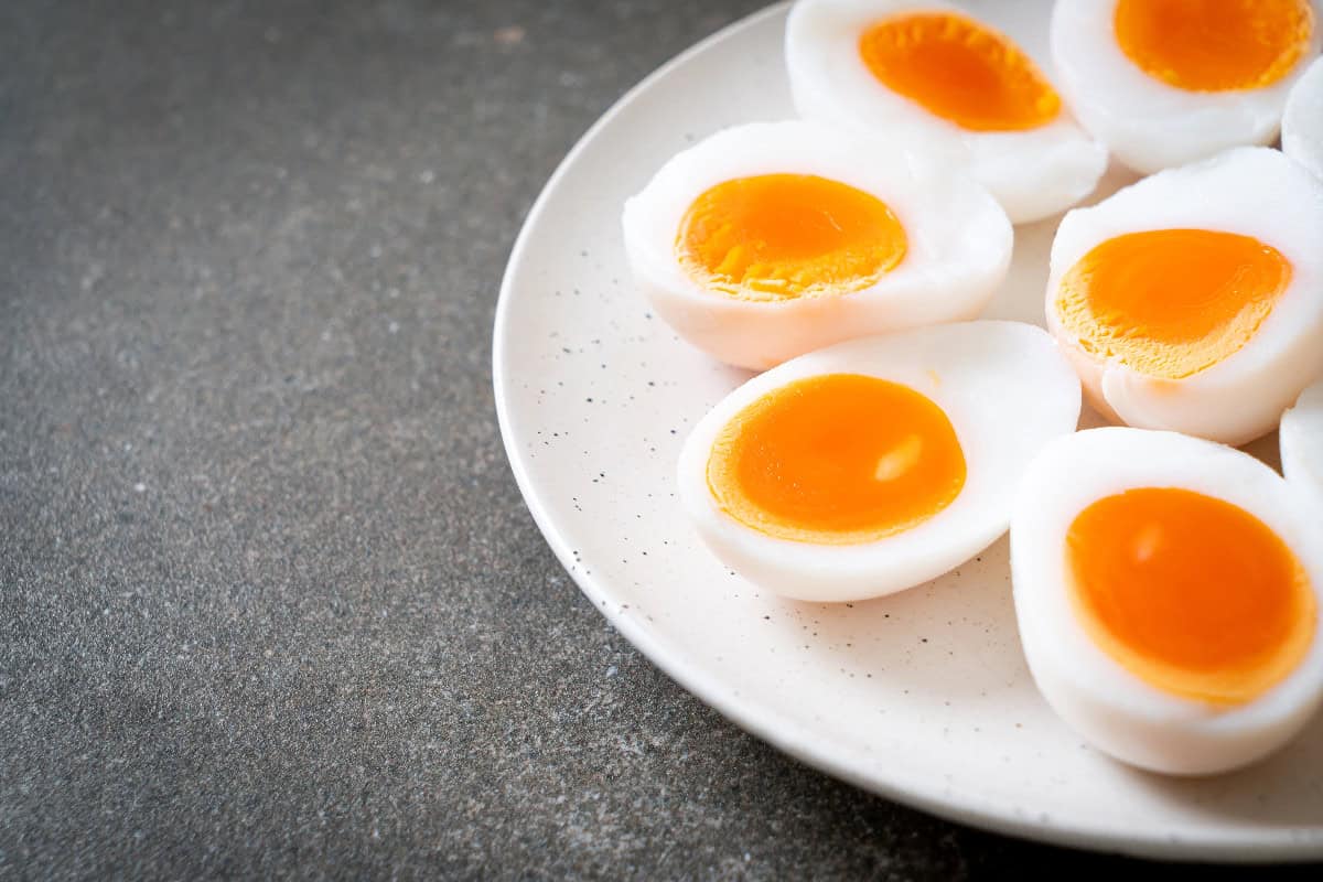 Soft-boiled eggs with bright orange yolks sliced in half and arranged on a plate.