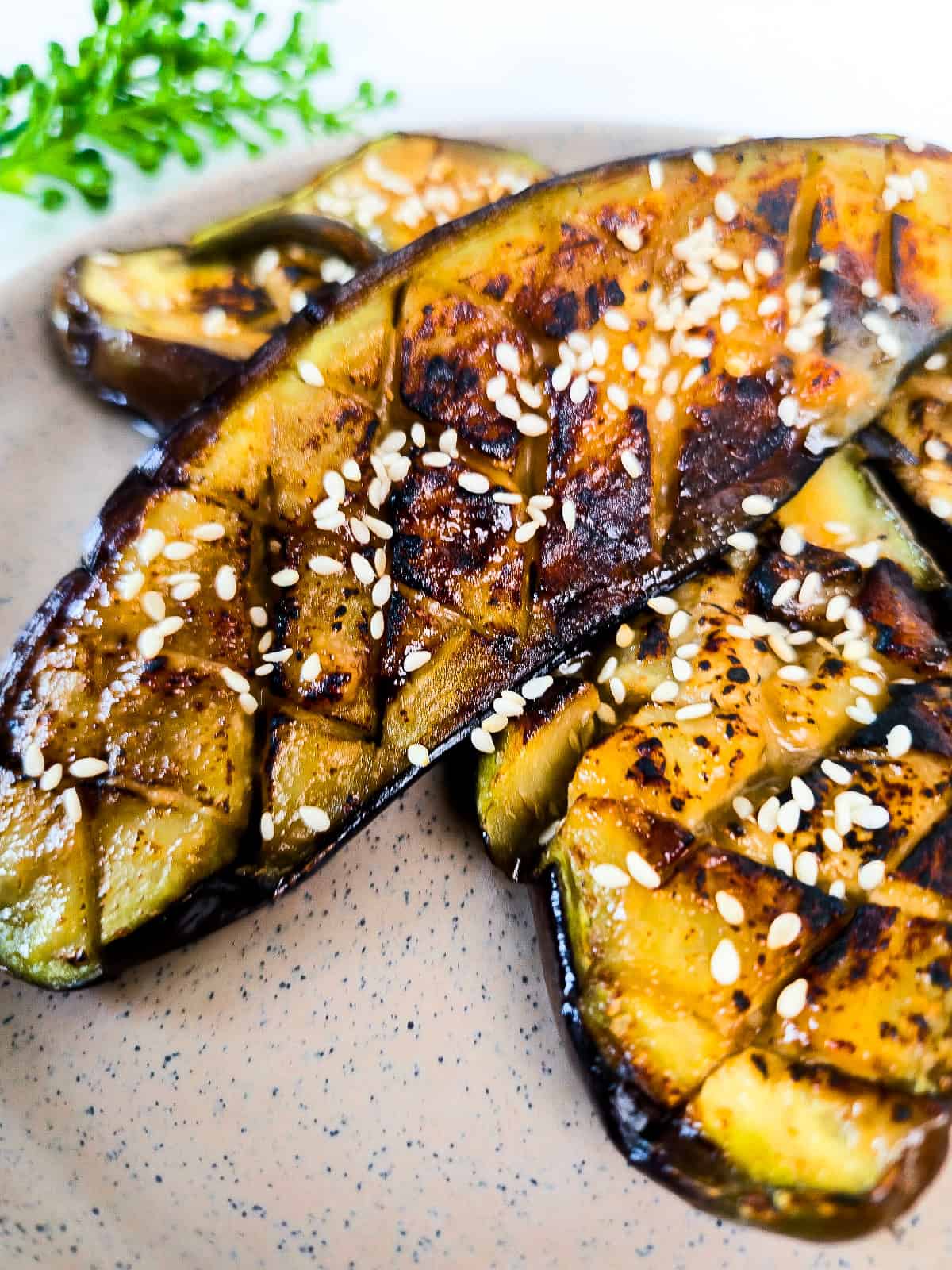 Close-up of caramelized miso glazed eggplant with sesame seeds, showing the tender roasted eggplant and golden-brown glaze.