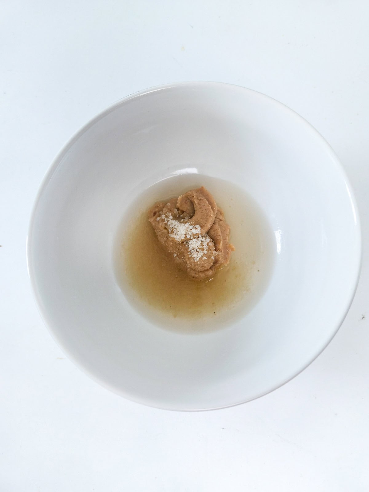 Miso paste, mirin, and sugar combined in a white bowl before mixing into a glaze.