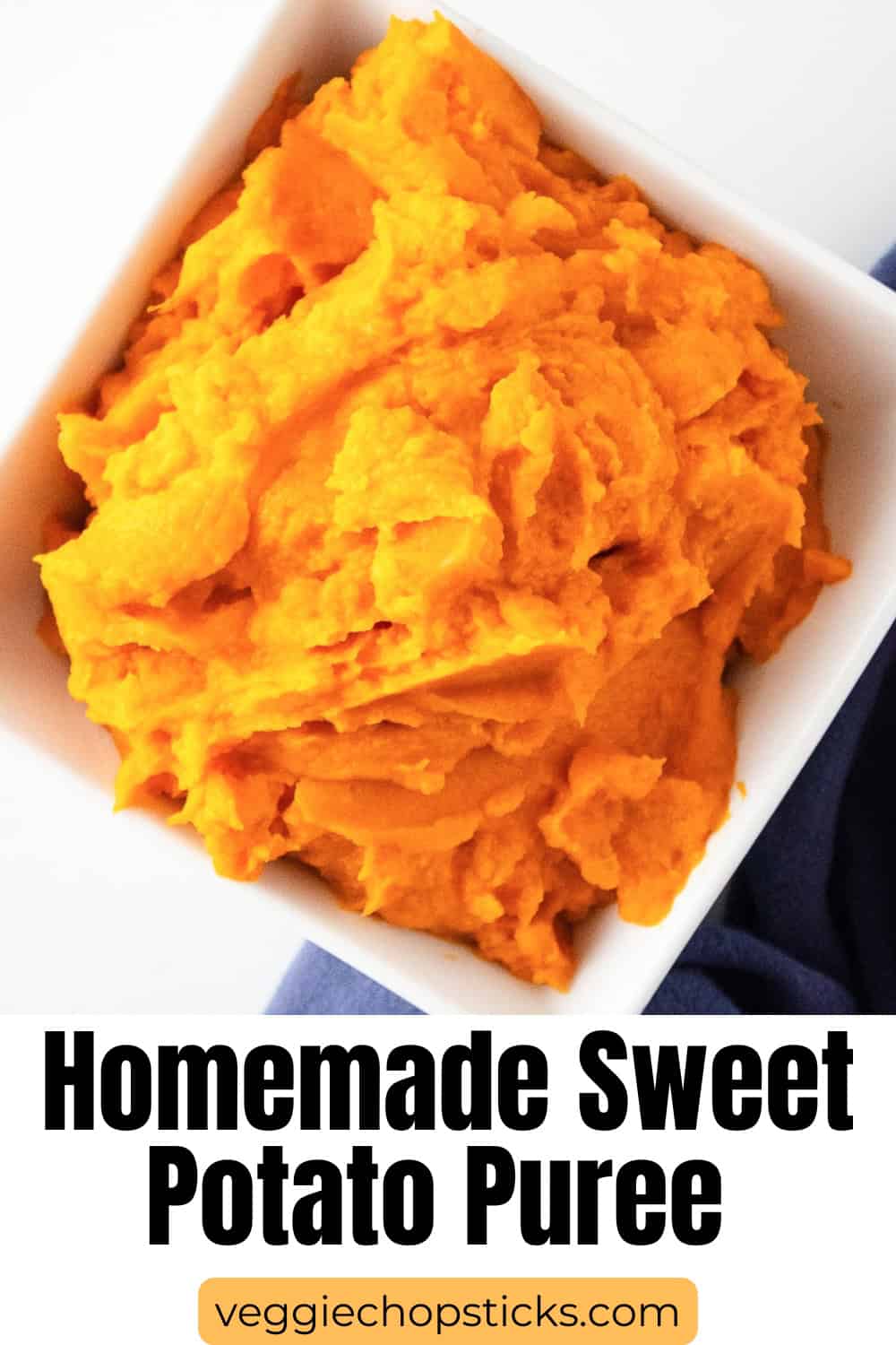 Overhead shot of sweet potato puree in a white bowl with a blue cloth beside it.