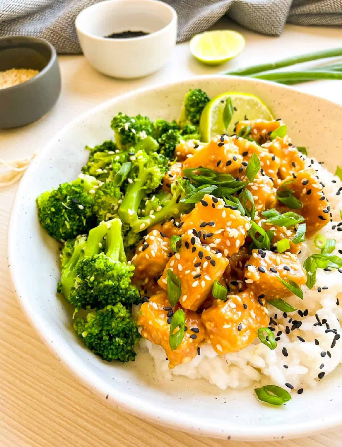 Close-up of creamy sesame tofu with steamed broccoli and rice garnished with sesame seeds.