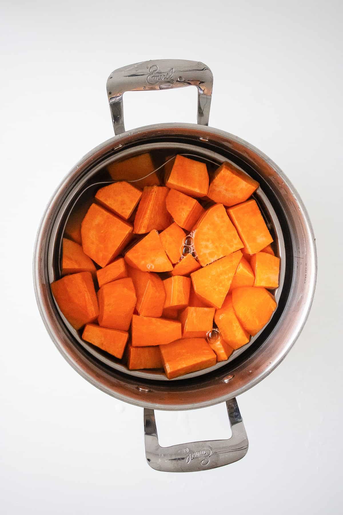 Cubed sweet potatoes boiling in a pot of water on the stovetop.