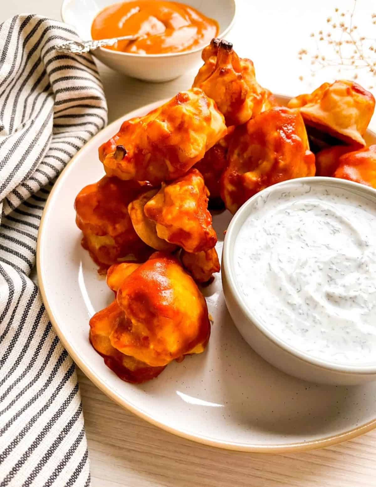 Close-up of crispy vegan buffalo cauliflower wings served with homemade dairy-free ranch dip.