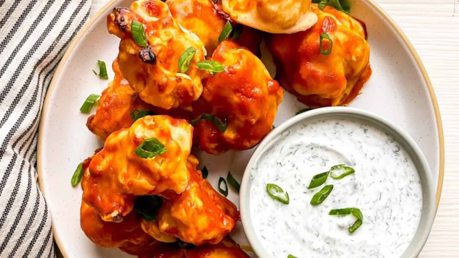 Vegan buffalo cauliflower wings with ranch dipping sauce served on a plate for a game day appetizer.