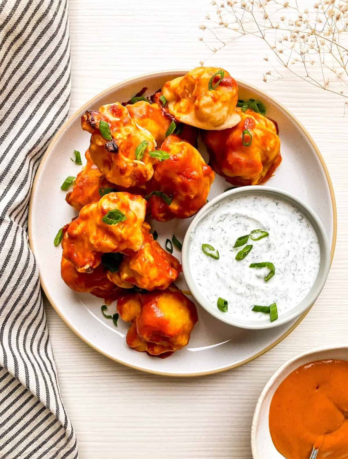 Vegan buffalo cauliflower wings with ranch dipping sauce served on a plate for a game day appetizer.