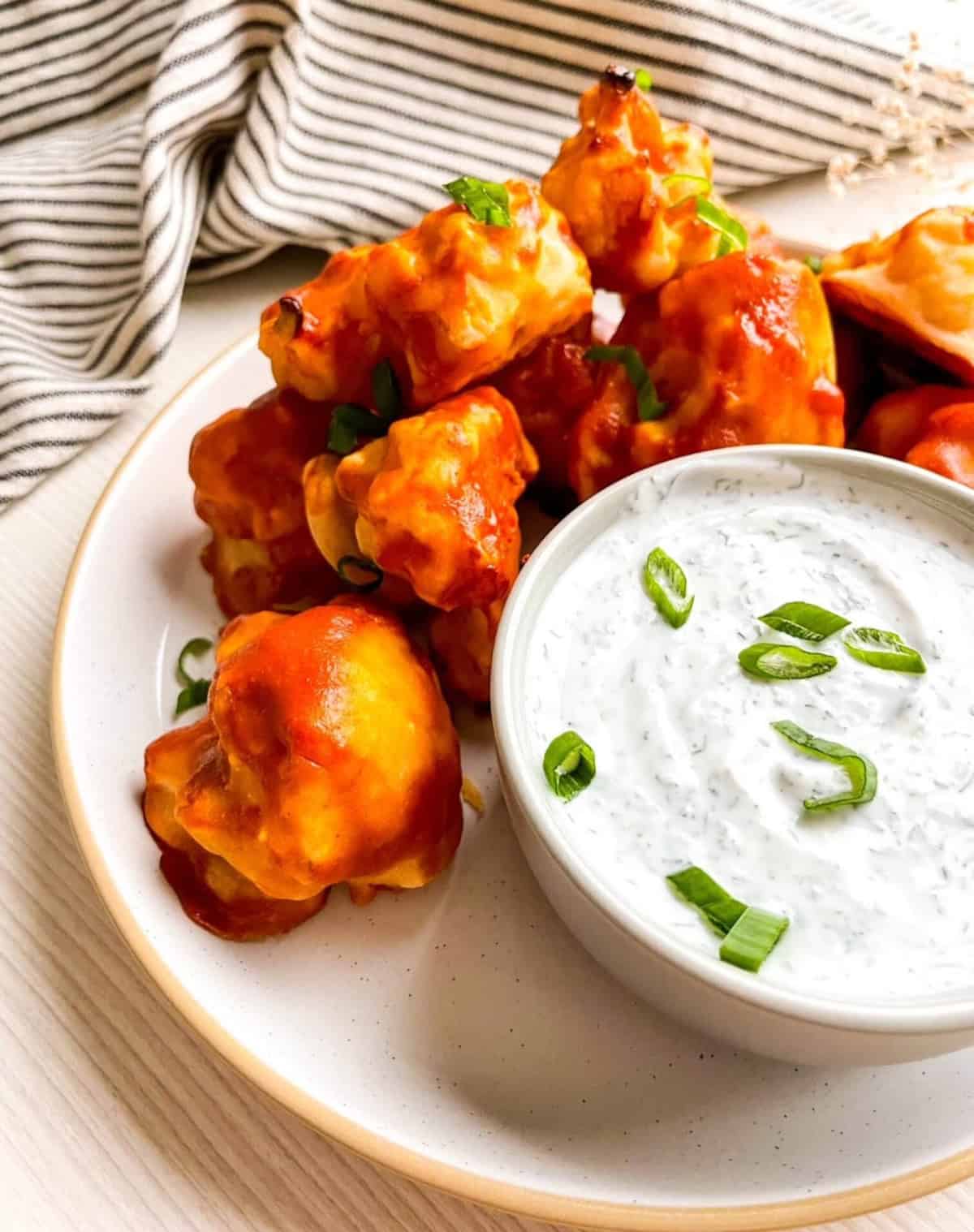 Buffalo cauliflower wings garnished with sliced green onions and served with creamy ranch dip.