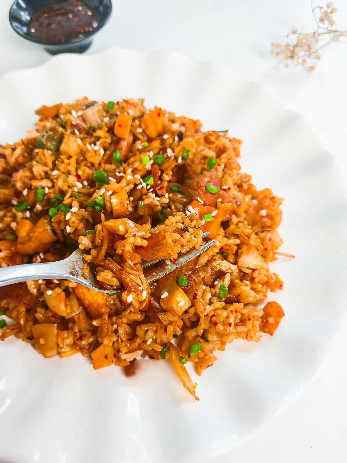 Close-up of vegan kimchi fried rice with kimchi, tofu, mushrooms, sesame seeds, and green onions.