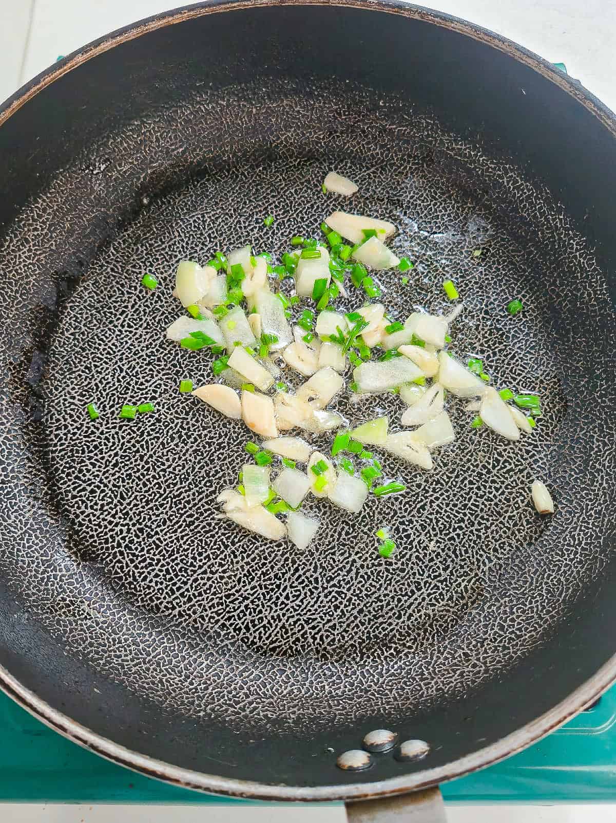 Garlic, diced onion, and green onions saut&eacute;ing in a skillet for vegan kimchi fried rice.