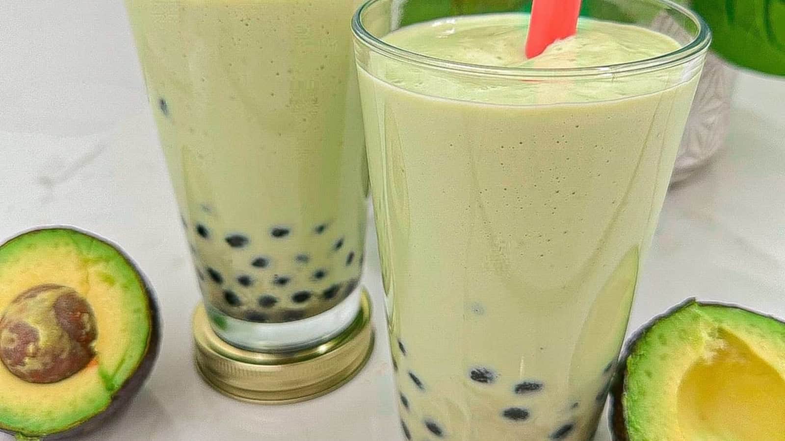Creamy avocado smoothie with chewy boba pearls in glasses with a red color straw.