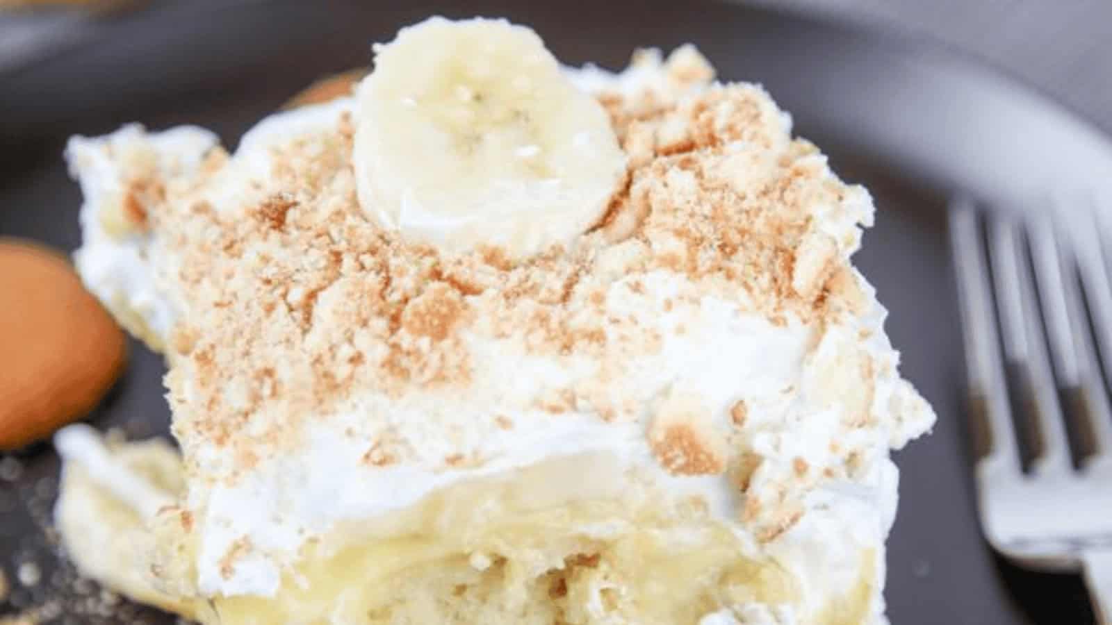 A slice of banana pudding cake topped with sliced bananas and crushed vanilla wafers.