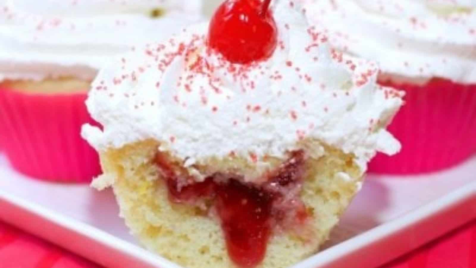 Cupcakes filled with cherry jelly and topped with sweet frosting.