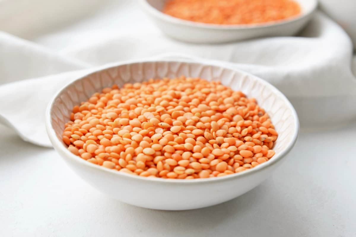 Red lentils in a shallow white bowl, a quick-cooking ingredient for microwave meals.