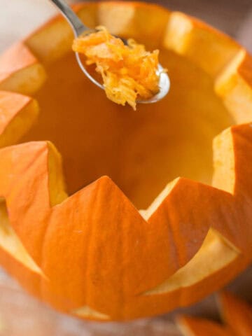 Scooping seeds and pulp from a carved pumpkin to help prevent rot and extend its freshness.