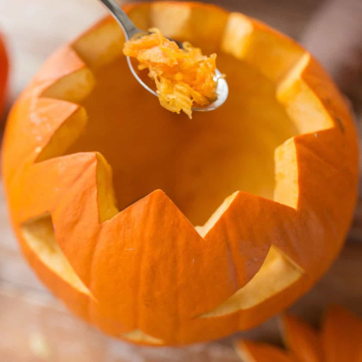 Scooping seeds and pulp from a carved pumpkin to help prevent rot and extend its freshness.
