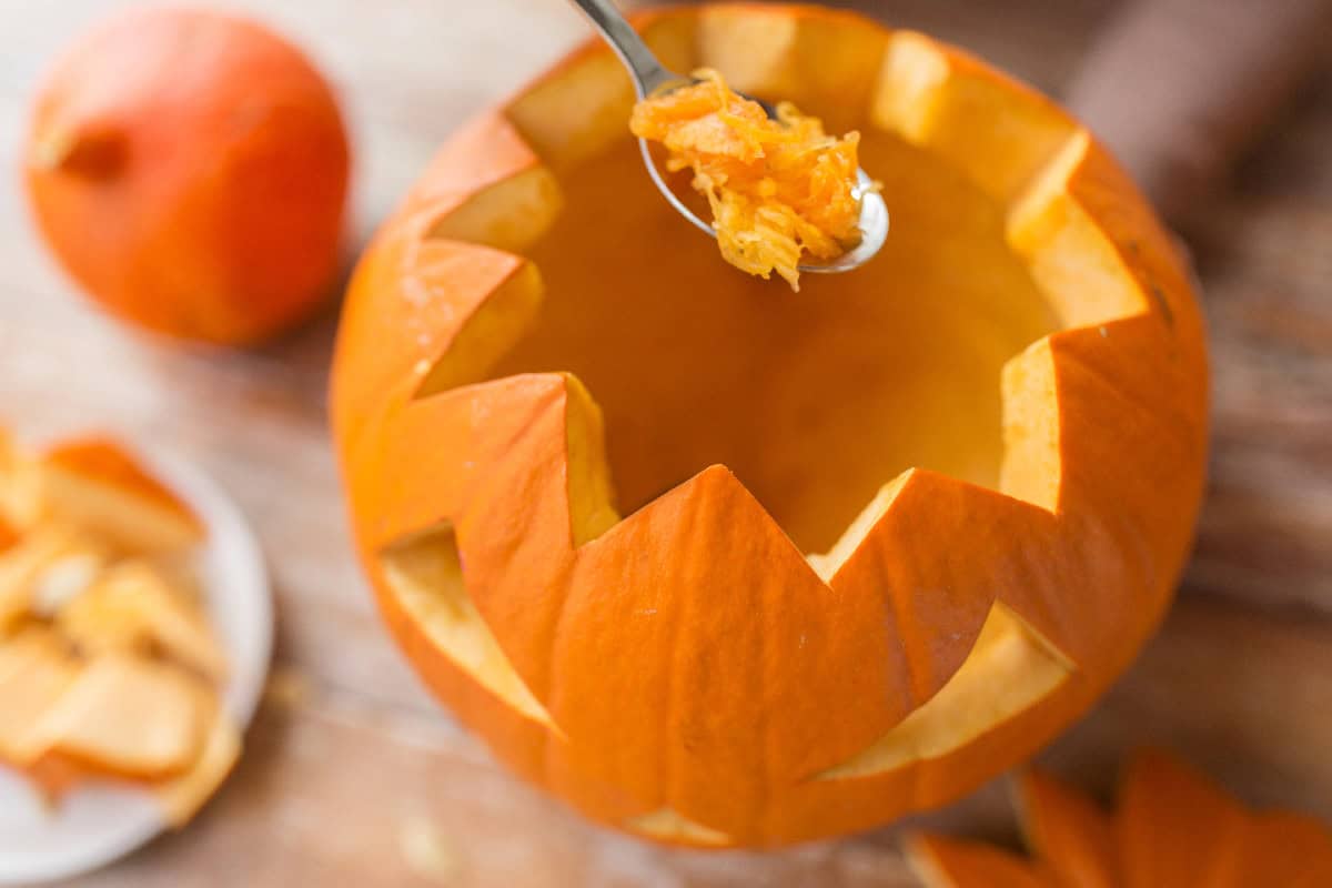Removing pumpkin pulp with a spoon before carving to help keep a jack-o'-lantern fresh longer.