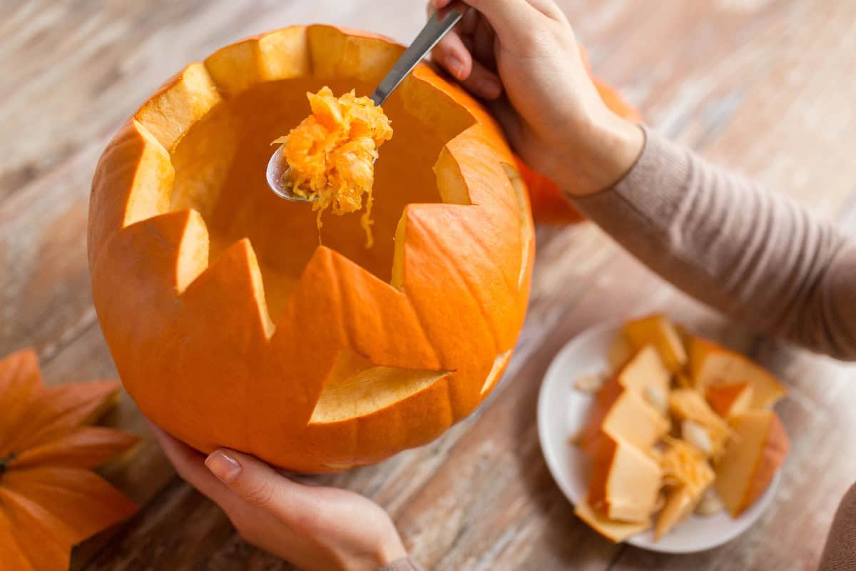 Scooping out pumpkin strings and seeds while carving a Halloween jack-o'-lantern.