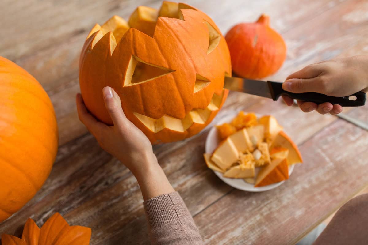 Carving a Halloween pumpkin with a knife to create a jack-o'-lantern that lasts longer.